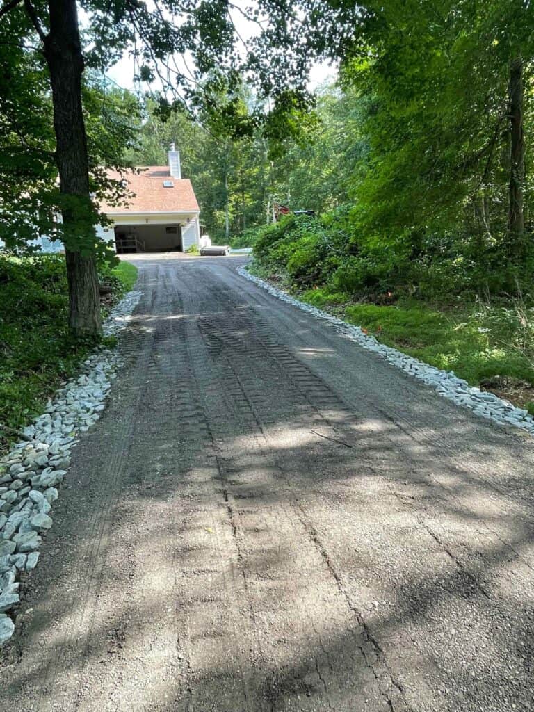 Freshly graded gravel driveway with crushed stone borders on both sides